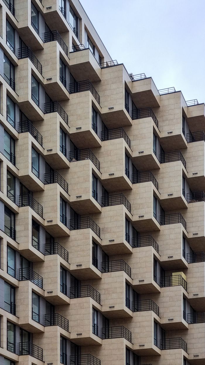 Close-up of a modern building with geometric balconies and glass windows, showcasing contemporary architecture.