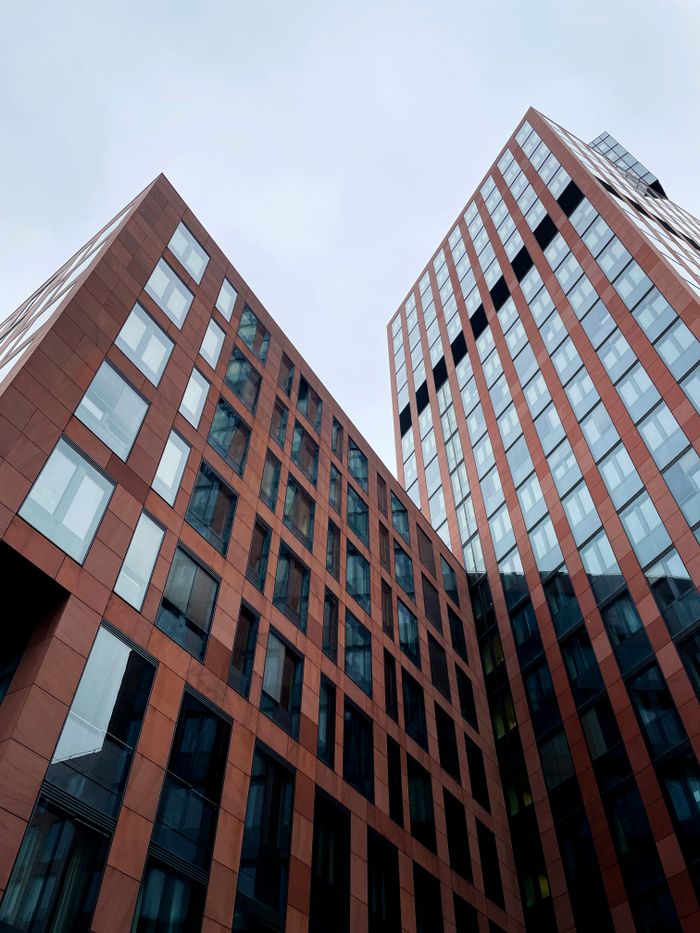 Dynamic view of contemporary office skyscrapers with glass facades set against a cloudy sky.