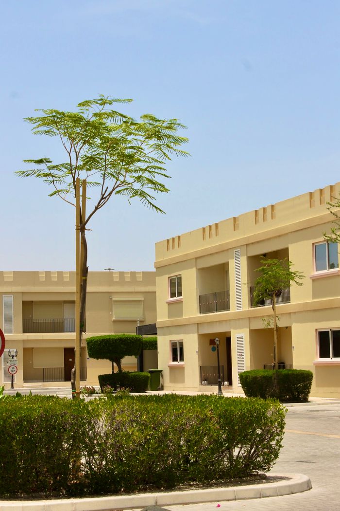 Sunny day view of a modern apartment complex with greenery and clear blue sky.